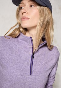 Hellvioletter Viertelreißverschluss-Pullover aus strukturiertem Stoff, mit einem kontrastierenden schwarzen Reißverschluss und einem Stehkragen. Glatte Oberfläche.