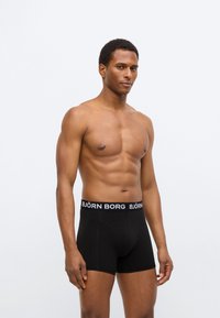 Μαύρο boxer με φαρδιά ελαστική μέση που φέρει το λευκό κείμενο "BJÖRN BORG". Λείο ύφασμα, εφαρμοστή σχεδίαση και μήκος μέχρι το μέσο μηρού.