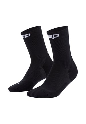 Schwarze Sportstrümpfe mit geripptem Textur, verstärktem Fersen- und Zehenbereich, mit weißem Logo am Bündchen. Mittlere Schafthöhe.