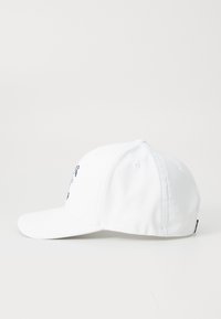 Hvit baseballcaps laget av stoff, med en sydd design foran, en buet skjerm og ventilasjonsåpninger på sidene.