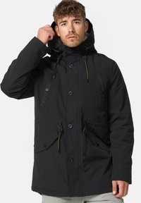 Parka noire avec capuche, dotée d'une fermeture éclair à l'avant, de deux grandes poches à l'avant et d'accents à cordon de serrage sur la capuche et à la taille.