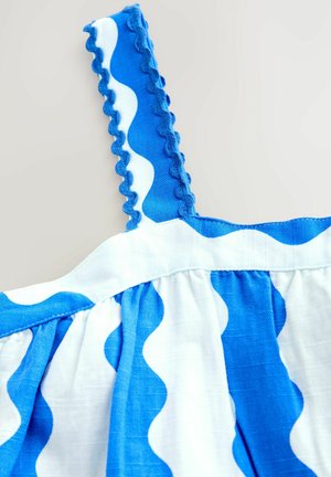 Detaliu al unei rochii cu un model albastru și alb, cu dungi ondulate, bretele texturate cu margini zimțate și țesătură pliată pentru volum.