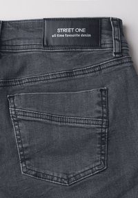 Musta farkut, joissa näkyy takatasku ja musta etiketti valkoisella tekstillä "STREET ONE all time favourite denim."