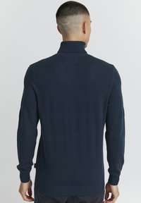 Maglione pullover blu navy con colletto alto, polsini a coste e motivo a strisce testurizzato sul retro. Tessuto lavorato a maglia, design aderente.