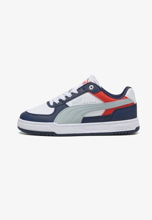 Baskets basses Puma avec panneaux blancs, bleu marine, rouge et gris clair, lacets blancs et semelle en caoutchouc, présentées de profil sur fond blanc.