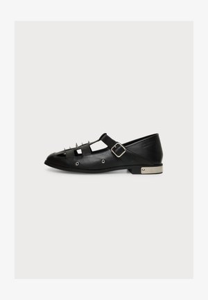 Schwarzer flacher Lederschuh mit silbernen Spikes oben, Cut-Out-Design, silberner Schnallenriemen und metallic Detail an der Ferse.