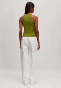 Aansluitend olijfgroene tanktop met een ronde halslijn en racerback ontwerp, gecombineerd met wijde witte broek met een gathersluiting in de taille.