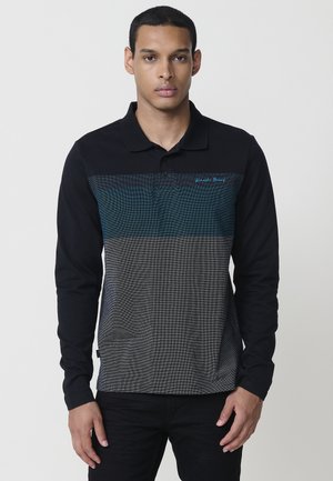 Polo de manga larga con parte superior negra y sección inferior con un patrón texturizado en azul oscuro y gris. Incluye un cuello y detalles de costura finos.