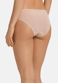 Slips in tinta nude, a vita alta, prodotti in tessuto morbido e leggero con una finitura trasparente. Presentano cuciture sottili lungo i bordi.