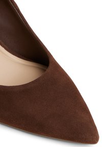 Décolleté in camoscio marrone con punta affusolata, dotata di una fodera interna liscia, caratterizzata da un design a taglio profondo e una superficie esterna testurizzata.