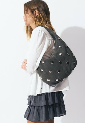 Gray suede shoulder bag adorned with metallic circular studs, featuring a zip closure and a soft, textured finish.