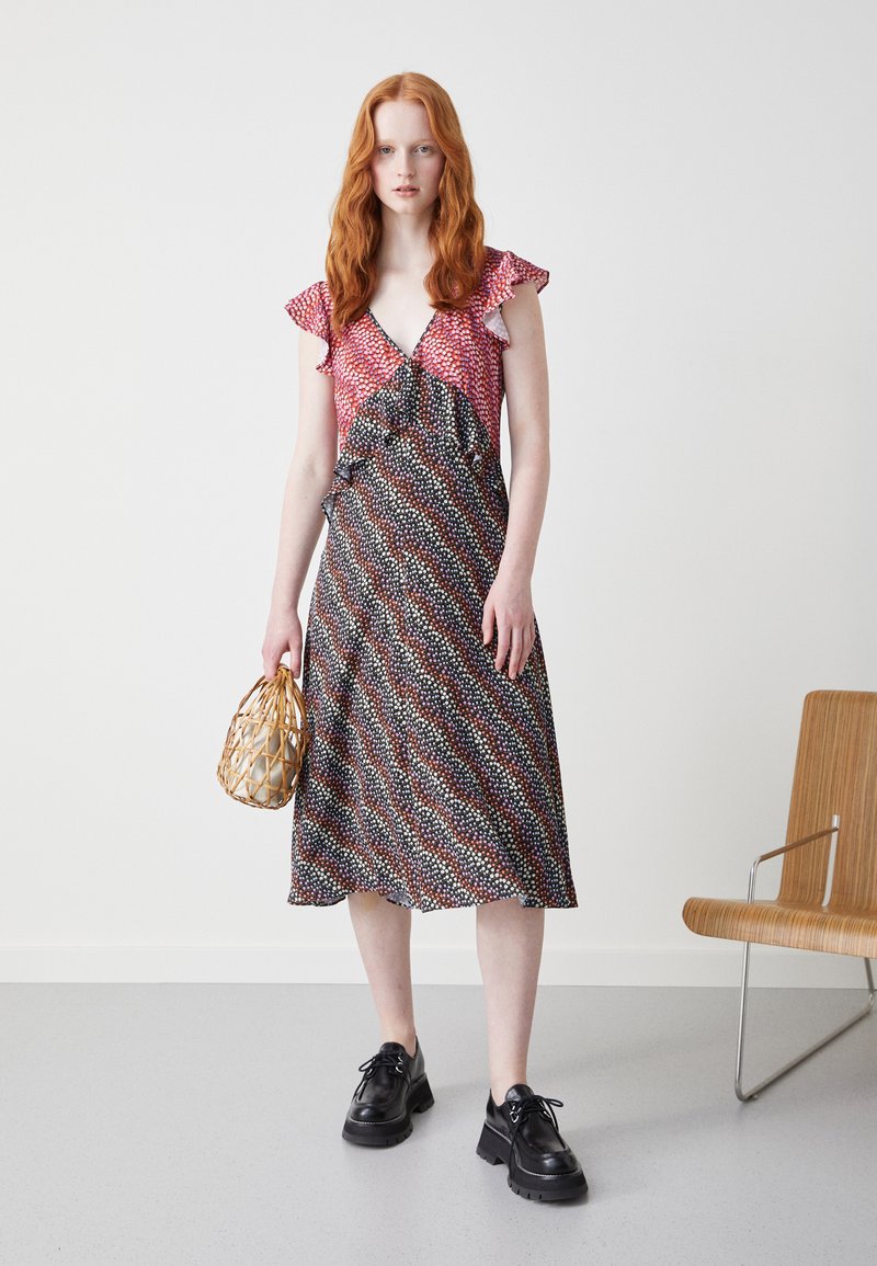 Vestido com padrão floral, com mangas franzidas, decote em V e design fluido. As cores incluem padrões em vermelho, preto e branco, com um corte a meio comprimento.