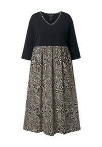 Černý top s výstřihem do V a třičtvrtinovými rukávy, doplněný vzorovanou béžovou sukní s geometrickými motivy. Uvolněný, A-liniový střih.