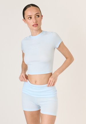 Svetlomodrý športový set obsahujúci krátky rukáv crop top a šortky s vysokým pásom. Vyrobené z rebrovanej textúry s detailom loga.