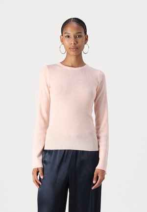  pull long-sleeve côtelé rose clair avec un col rond, au design ajusté et à la texture douce, associé à un pantalon en satin foncé.