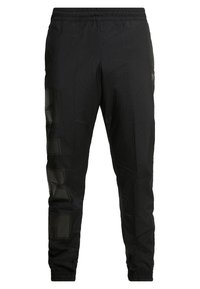 Svarta lätta nylonträningsbyxor med elastisk midja och cuffs, med subtil broderad logotyp på vänster ben.