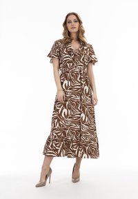 Brun og hvid zebra print maxi kjole med korte flæseærmer, en indsnævret talje og en svungne kant. Bruges med beige højhælede sko.