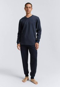 Ensemble de vêtements d'intérieur bleu marine comprenant un haut à manches longues avec col en V et un pantalon assorti avec poignets côtelés. Confectionné dans un tissu doux, design minimaliste.