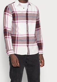 Camicia a maniche lunghe da uomo a quadri in bianco, bordeaux e grigio. Presenta un motivo a quadri multicolore, colletto button-down e una pattina frontale.
