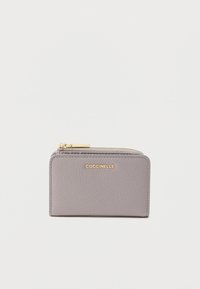 Harmaa nahkalompakko, jossa on teksturoitu viimeistely, kullanvärinen logo ja vetoketjullinen suljin. Kompakti suorakulmainen muoto ja siistit linjat.