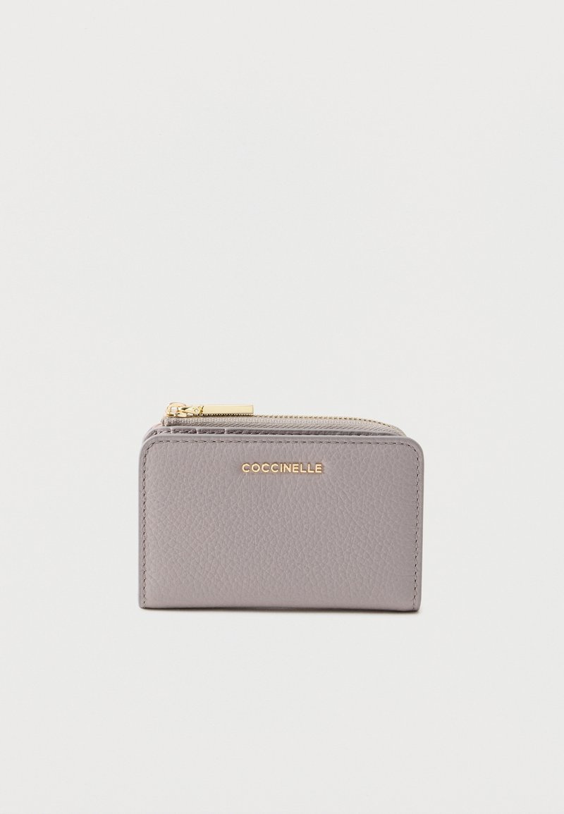 Harmaa nahkalompakko, jossa on teksturoitu viimeistely, kullanvärinen logo ja vetoketjullinen suljin. Kompakti suorakulmainen muoto ja siistit linjat.