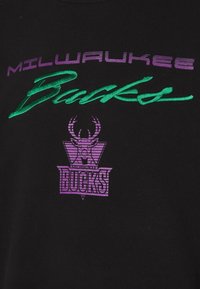 Czarna bawełniana koszulka z przyhaftowanym tekstem "MILWAUKEE Bucks" w kolorze fioletowym i zielonym oraz fioletowym logo graficznym z porożem jelenia.