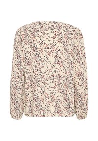 Chemisier à manches longues en crème avec un motif floral tourbillonnant en rouge et bleu marine. Présente des poignets élastiqués et une coupe décontractée.