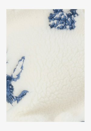 Manta suave de forro polar en blanco con diseños florales bordados en azul. Presenta una superficie texturizada que resalta los detalles intrincados del bordado.