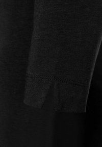 Schwarzes kurzärmliges T-Shirt mit abgerundetem Saum und einem kleinen Seitenschlitz. Weiche Stoffstruktur mit sauberer Naht entlang der Kanten.