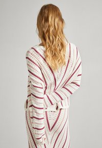 Adītais džemperis ivorijas krāsā ar bordo un rozā diognālo svītru rakstu, ar brīvu piegriezumu, garām piedurknēm un teksturētu atvērtu austību.