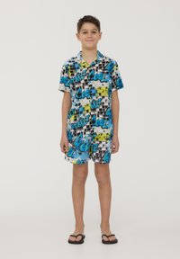 Set di camicia a maniche corte e pantaloni corti in blu, nero e giallo con stampe grafiche; realizzato in tessuto leggero; abbinato a ciabatte nere.