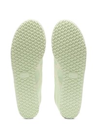 Zelené gumové podešve tenisek s texturovanými trojúhelníkovými vzory. Obsahuje logo vyražené na oblasti paty s čistým, minimalistickým designem.