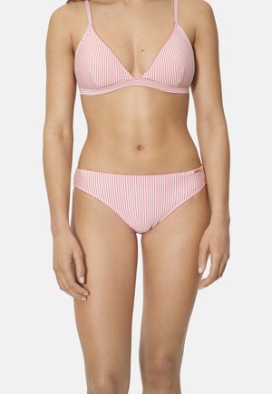 Mujer con bikini de rayas rosa y blanca con tirantes ajustables, de pie frente a un fondo claro y liso.