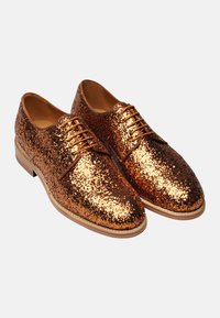Scarpe eleganti marroni in oro brillanti, con superficie texturizzata, punta arrotondata e design con lacci, dotate di una suola in legno chiaro a contrasto.
