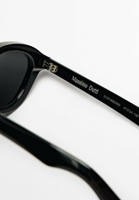 Svarta solglasögon med glänsande acetatramar. Funktioner inkluderar en liten metalldetalj på gångjärnet och det ingraverade varumärket "Massimo Dutti" på armen.