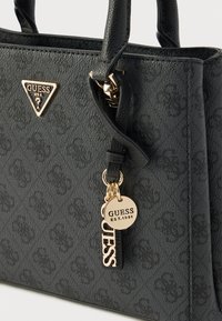 Sort tekstureret håndtaske med gulddetaljer, med en trekantet logo, nøglekæde-accenter og et struktureret design.