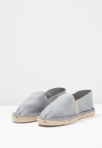 Gray cotton espadrilles with a woven jute sole, slip-on design, and open heel. Features simple stitching and no additional patterns.