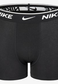 Črne boksarice za moške z oblikovanim krojem. Imajo kontrastni bel Nike logotip na elastičnem pasu. Narejene so iz mehkega blaga.