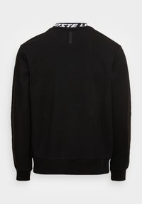 Sweat-shirt noir avec col rond, poignets et ourlet côtelés, arborant une bande logo blanche distincte au niveau du col. Texture lisse.