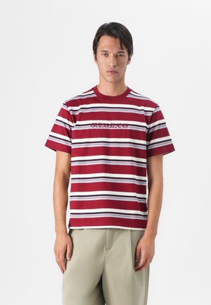 Camiseta de rayas rojas y blancas con mangas cortas, que presenta "GUESS JEANS" bordado en burdeos. Cuello redondo, ajuste relajado.