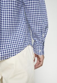 Blauwe en witte geblokte overhemd met lange mouwen en manchetknoopjes, gecombineerd met lichtgekleurde broeken, gemaakt van zachte stof en met een relaxed fit.