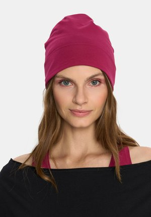 Różowa bawełniana czapka o miękkiej teksturze i dopasowanym kroju, z podwiniętym brzegiem dla wygodnego noszenia. Tło w neutralnym kolorze.