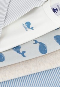Bomullskläder staplade; inkluderar randiga tyger i blått och vitt, krämfärgat med valtryck och en beige textur, alla släta och mjuka.