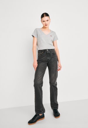 Grå v-hals t-skjorte med korte ermer, paret med høy midje svart denim jeans. Antrekket har svarte joggesko med gummisåler.