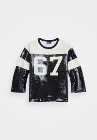 Dlouhý rukáv s flitry, námořnicky modrý kulatý výstřih. Má stříbrné a námořnicky modré pruhy, velké bílé číslo "67" na přední straně, lesklý povrch po celé délce.