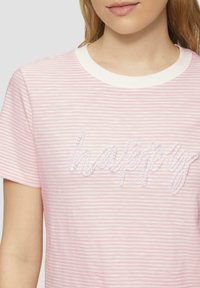 Roze gestreepte t-shirt met korte mouwen en een witte ronde hals. Bevat de tekst "happy" geborduurd in parelachtige kraaltjes over de borst.