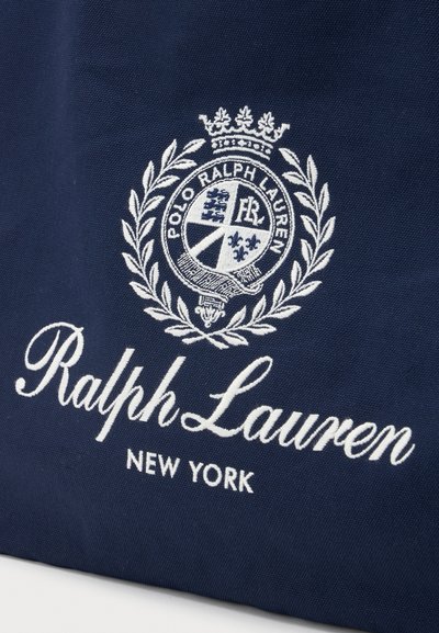 Navy fabric with white embroidered Ralph Lauren logo, crest with laurel wreath and crown, text reads "Polo Ralph Lauren" and "New York."