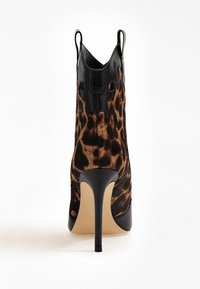 Höga ankelskor med leopardmönstrad tyg och dekorativt topp i svart läder, visade från baksidan på en vit bakgrund.