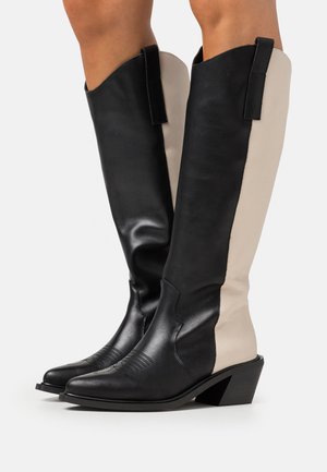 Bottes montantes en cuir noir et beige avec un bout pointu, des accents texturés et un talon empilable. Caractéristiques d'un design bicolore et de poignées de tirage.