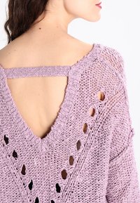 Fialový pletený svetr s designem ve tvaru V a výřezem na zádech, s texturovaným vzorem a otevřenými detaily.